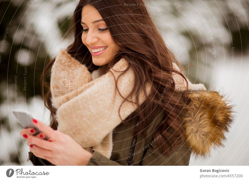 Lächelnde junge Frau mit Mobiltelefon im Winter im Freien attraktiv schön lässig Kaukasier Zelle Funktelefon kalt Mitteilung frieren Glück Lifestyle Mobile