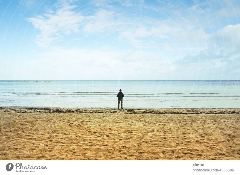 Ein Mann allein am Sandstrand, auf das stille Meer blickend / Urlaub / Entspannung / Sehnsucht Ostsee Person Strand Ufer Relaxen philosophieren Wasser Ferne