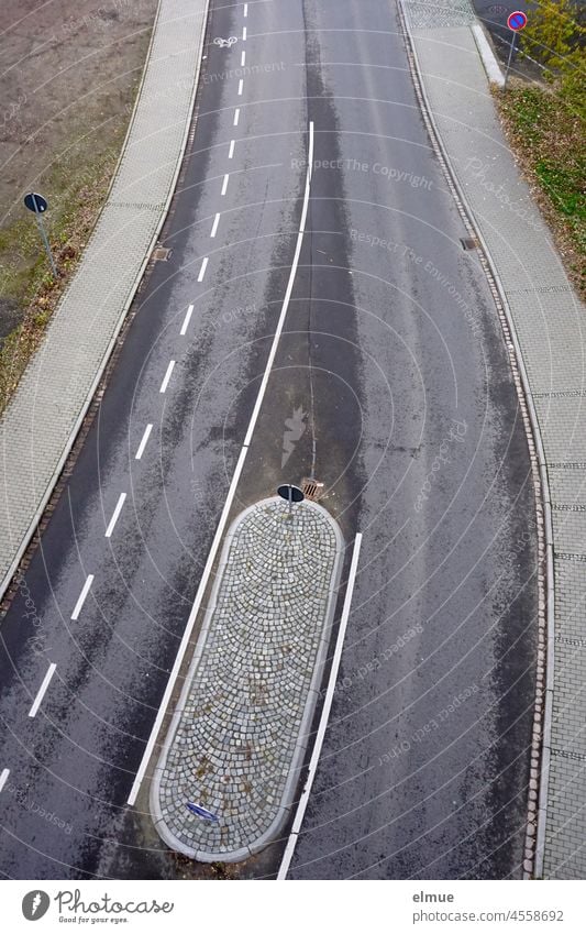 Draufsicht auf eine asphaltierte Straße mit einer gepflasterten Verkehrsinsel, einem markierten Radweg und Verkehrszeichen - eingeschränktes Halteverbot - / Straßenverkehr