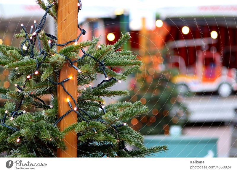 Tannenbaum mit Lichter am Weihnachtsmarkt. Verschwommene Hintergrund mit einem Karussell-Auto. Rundes Bokeh. weihnachten lichter tannenbaum karussell auto