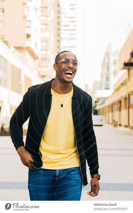 Fröhlicher afroamerikanischer Mann auf der Straße heiter Brille positiv Lächeln Optimist Porträt Inhalt genießen urban Großstadt Freude Glück Afroamerikaner