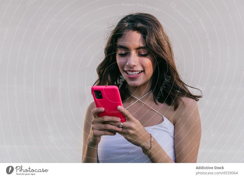 Lächelnde Frau mit Smartphone auf weißem Hintergrund Porträt Funktelefon benutzend Browsen Texten Talkrunde Inhalt Textnachricht Freude positiv angenehm SMS