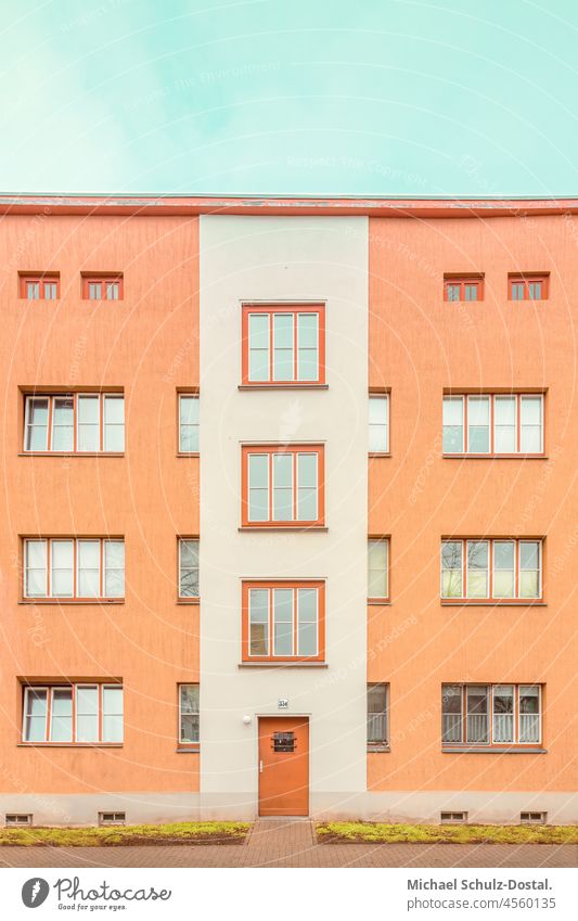 Bauhaus-Block in Orange mir roter Tür grün rasen Menschenleer Bauwerk Haus Farbfoto Moderne Architektur Magdeburger Moderne mietskaserne Fenster fläche