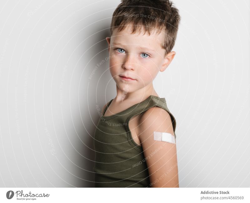 Schulkind nach Impfung mit Pflaster am Arm Junge Kind Impfstoff heiter Stoß ernst Schuss Einspritzung Gesundheit Arme Motivation Kindheit abstützen medizinisch