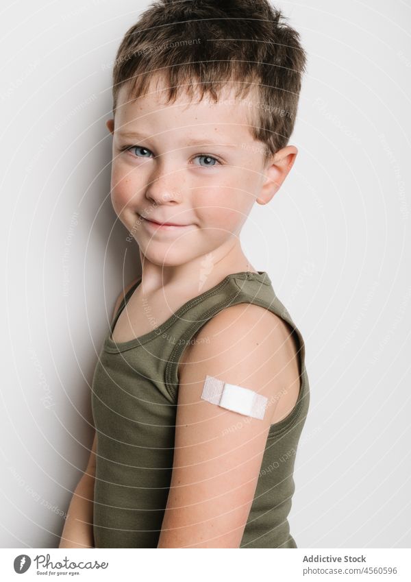 Schulkind nach Impfung mit Pflaster am Arm Junge Kind Impfstoff Stoß Schuss Einspritzung Gesundheit Arme Motivation Kindheit abstützen medizinisch Seuche