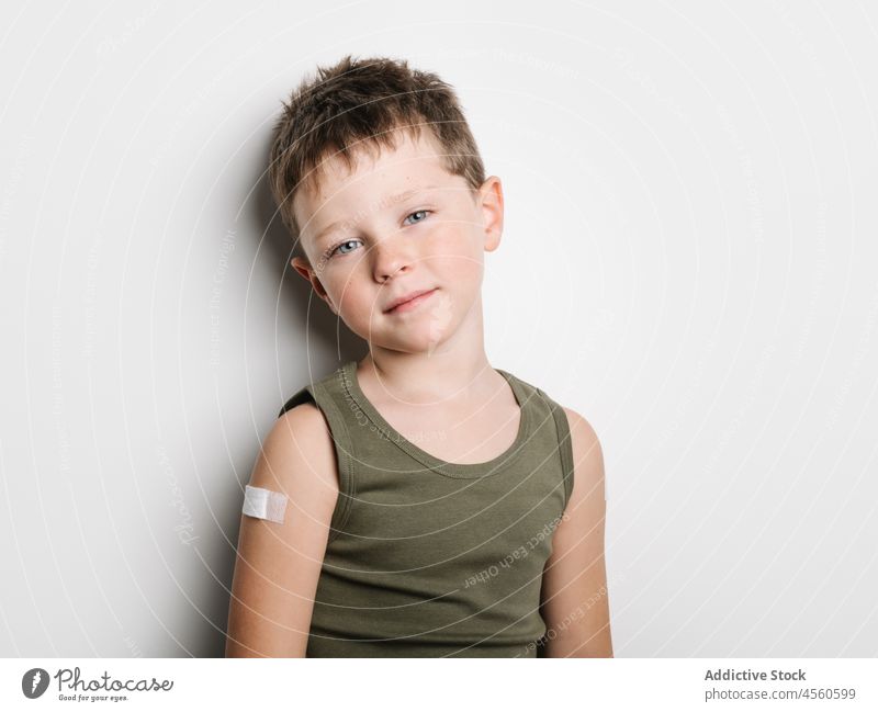 Schulkind nach Impfung mit Pflaster am Arm Junge Kind Impfstoff Stoß Schuss Einspritzung Gesundheit Arme Motivation Kindheit abstützen medizinisch Seuche