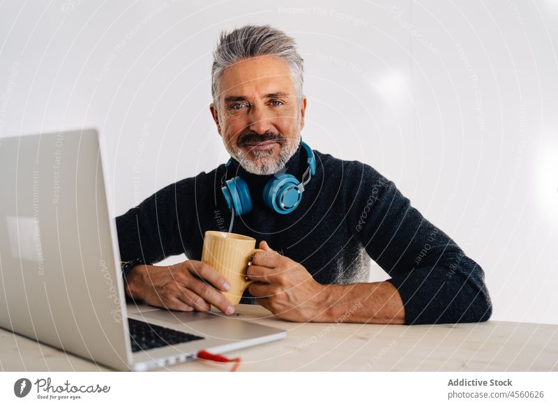 Älterer Blogger ruht sich mit einer Tasse Tee im Studio aus Mann trinken Podcast Ausstrahlung Mikrofon Laptop ruhen Aufzeichnen Arbeitsbereich Becher Pause