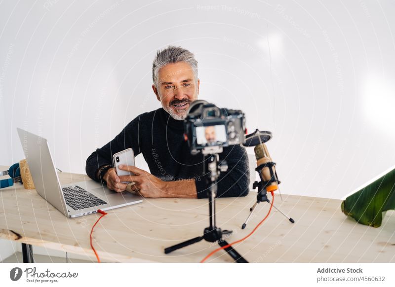 Hochrangige Meinungsbildner arbeiten an einem Tisch in einem modernen Arbeitsumfeld Mann Blogger Lächeln Ausstrahlung Podcast Mikrofon Laptop Aufzeichnen