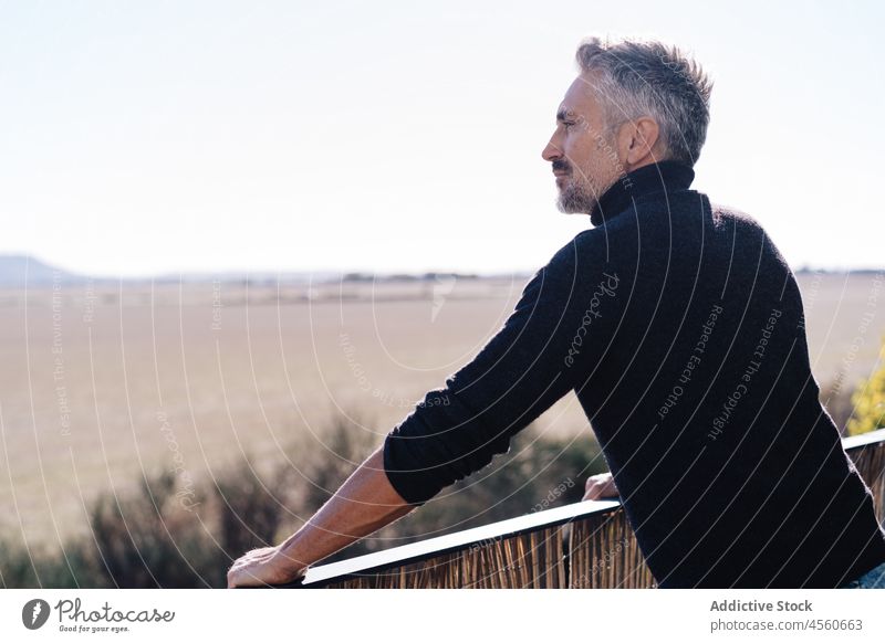 Älterer Mann auf Balkon stehend Landschaft bewundern nachdenken beobachten Reling Ansicht Himmel männlich alt Terrasse Gelassenheit Zaun gealtert Senior älter
