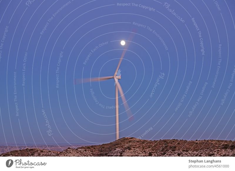 Bild einer rotierenden Windkraftanlage im Abendlicht mit Vollmond Windmühle Elektrizität Energie Umwelt Turbine regenerativ Kraft Himmel Natur Erzeuger Ökologie