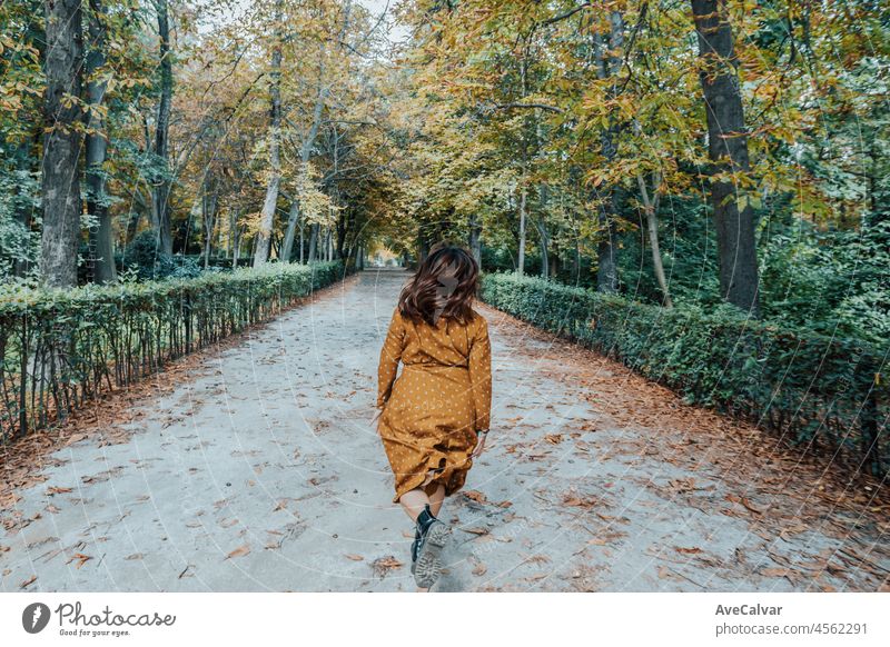 Frau, die auf einem Parkweg während der Herbstzeit läuft Boho Bohemien Freiheit Hipster Glück jung Porträt Kleid Kaukasier Frisur Lippen Aussehen Erholung