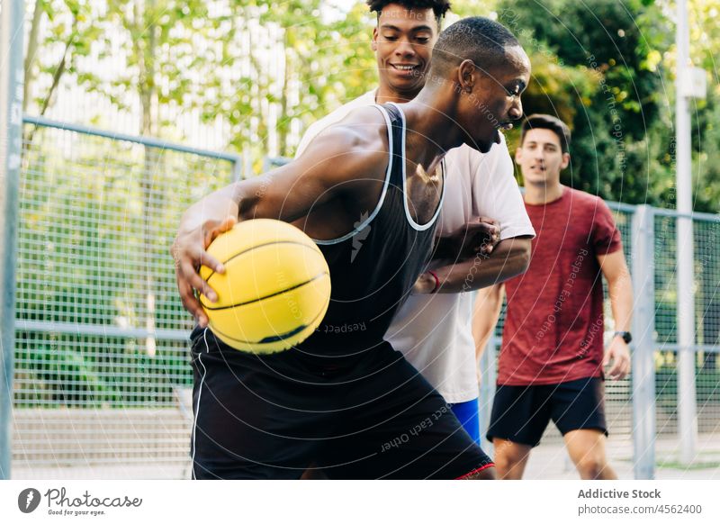 Eine Gruppe von Freunden springt und wirft den Ball hoch Männer werfen Basketball spielen Spieler Straße Sport positiv Mann heiter vielfältig rassenübergreifend