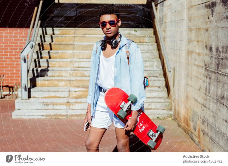 Junger schwarzer Mann auf der Straße mit einem Skateboard Teenager Schüler Schule Amerikaner Technik & Technologie jung Glück Shorts lässig Großstadt Freizeit
