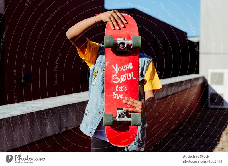 Junger Mann versteckt sein Gesicht mit einem Skateboard Skateboarderin Dachterrasse unkenntlich Großstadt posierend Freizeit Lifestyle Beteiligung männlich