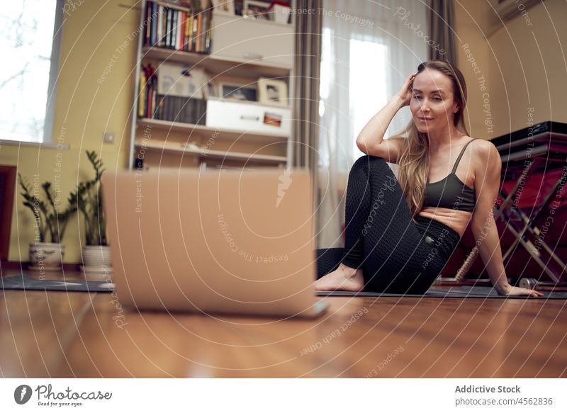 Frau beobachtet Yogastunde am Laptop Training Gesunder Lebensstil Wellness Video Tutorial Lektion online Funktelefon Wohlbefinden üben Wohnzimmer schlank Licht