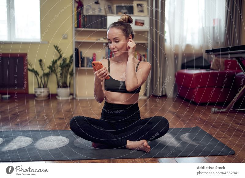 Sportliche Frau surft auf der Matte auf ihrem Smartphone Yoga Training Gesunder Lebensstil Wellness Browsen online Textnachricht Funktelefon Wohlbefinden üben