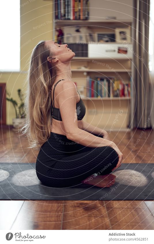 Frau auf einer Matte sitzend Yoga Training Gesunder Lebensstil Wellness Wohlbefinden üben Wohnzimmer schlank Appartement Gesundheit heimwärts sportlich Dame