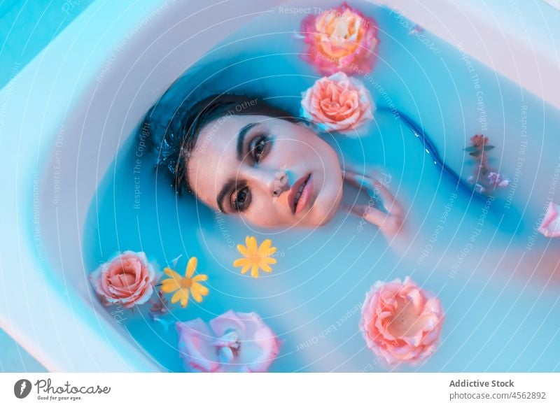 Junge Frau in Badewanne mit Blumen in blauem Licht nasses Haar sinnlich Lügen Melancholie Model verführerisch Angebot Verlockung filigran ruhig