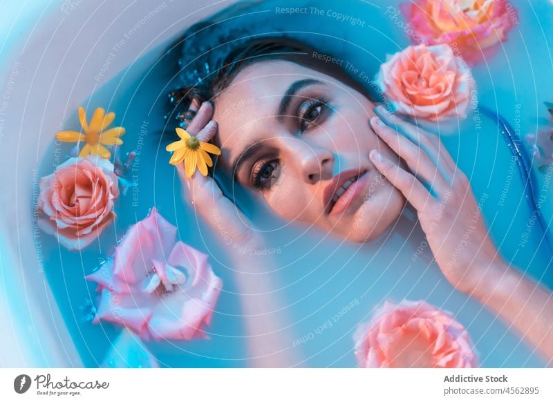 Junge Frau in Badewanne mit Blumen in blauem Licht nasses Haar sinnlich Lügen Melancholie Model verführerisch Angebot Verlockung filigran ruhig