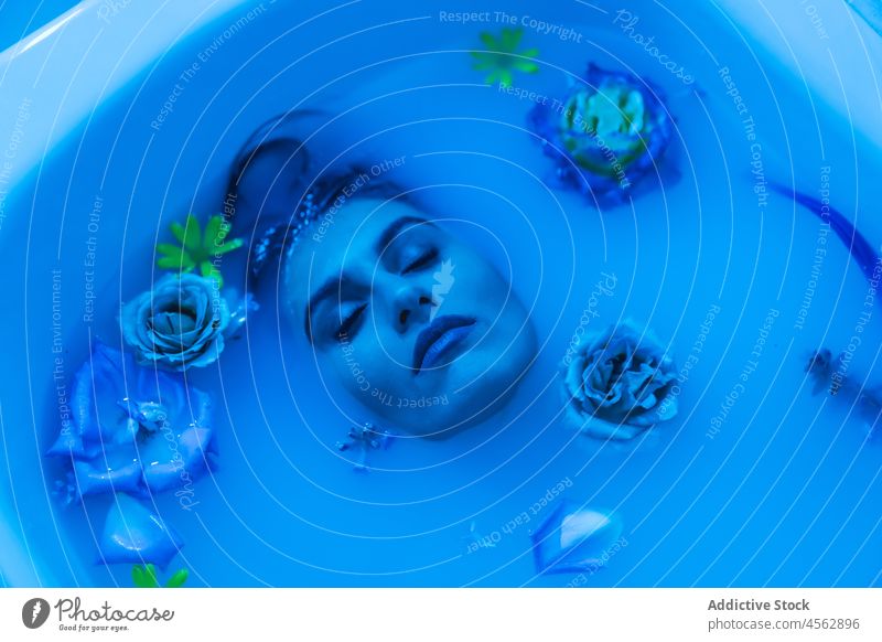 Junge Frau in Badewanne mit Blumen in blauem Licht nasses Haar sinnlich Lügen Melancholie Model verführerisch Angebot Verlockung Porträt filigran ruhig