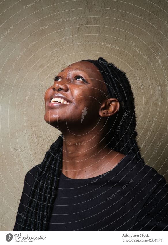 Lächelnde schwarze Frau sitzt auf dem Boden im Studio heiter positiv Vorschein Frisur Glück froh Zahnfarbenes Lächeln Optimist Afroamerikaner Stil lässig
