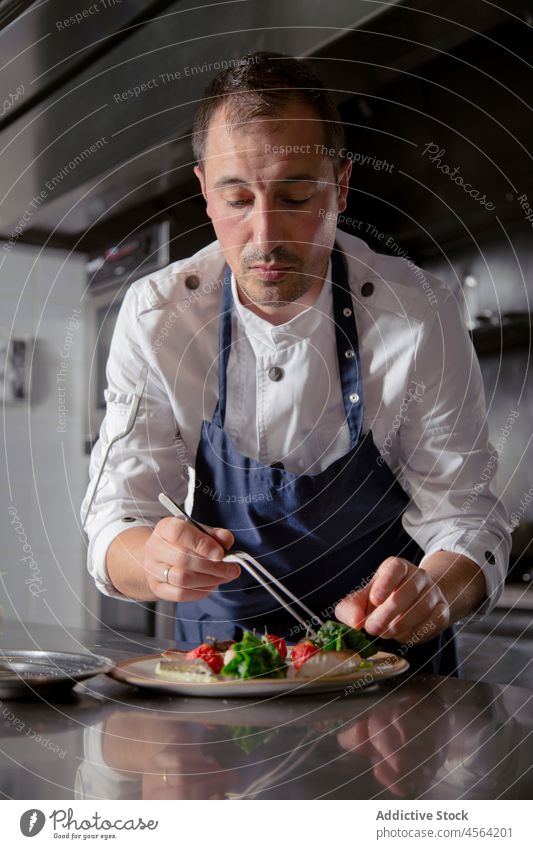 Fokussierter männlicher Koch beim Salatmachen im Restaurant Mann Haute Cuisine Mahlzeit dienen Pinzette Salatbeilage Exquisit Prozess anspruchsvoll achtsam