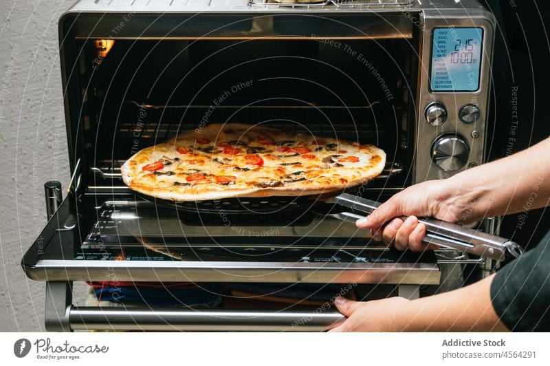 Crop-Frau nimmt eine Pizza aus dem Ofen Koch Mahlzeit gebacken Küche heiß bereit gekocht nehmen lecker Käse Tomate Pilz Lebensmittel vorbereiten Speise