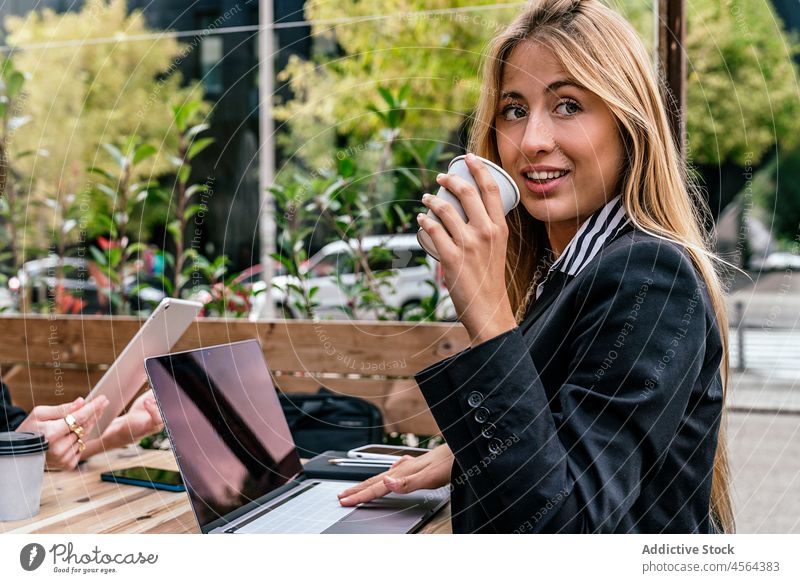Geschäftsfrau mit Kaffee am Tisch mit Laptop in einem Cafe Café Terrasse online Browsen Arbeit Business Heißgetränk modern Straße Zeit verbringen Großstadt