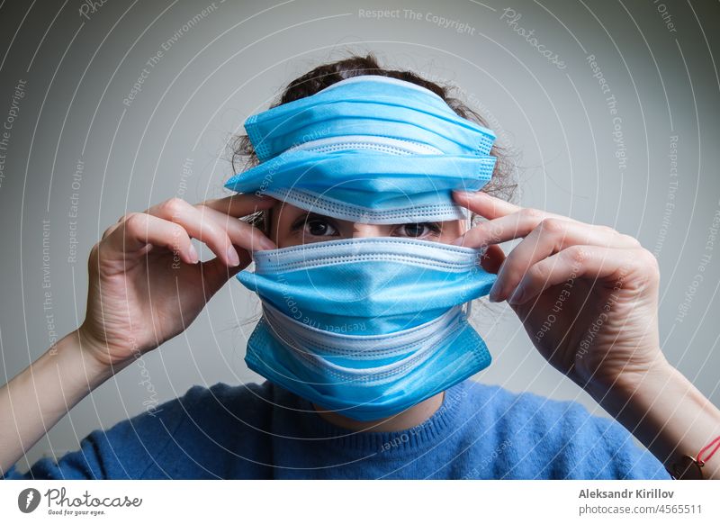 Eine Frau bedeckt ihr Gesicht mit mehreren medizinischen Masken medizinische Maske COVID Virus Seuche Freiheit Einschränkung Sperrung Verbot Isolation