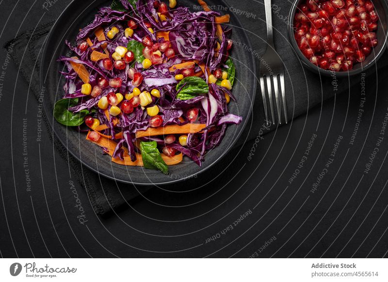 Hausgemachter Purpurkohlsalat mit Mais, Karotten, Granatapfel und Spinat Lebensmittel Granate Möhre weiß Hintergrund frisch Vegane Ernährung Diät