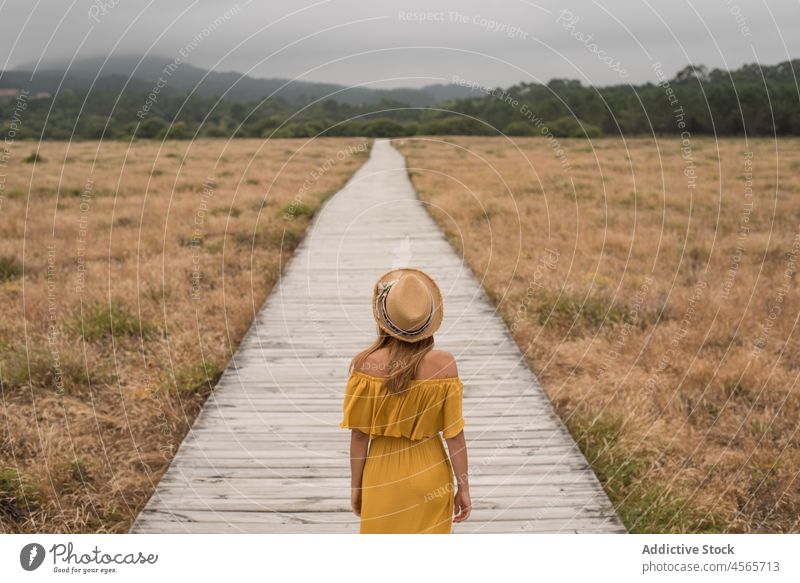 Anonyme Frau, die auf der Promenade im Grünen spazieren geht Düne Fußweg Natur Wiese Gras Landschaft corrubedo Galicia Weg Spanien hölzern Feld Spaziergang