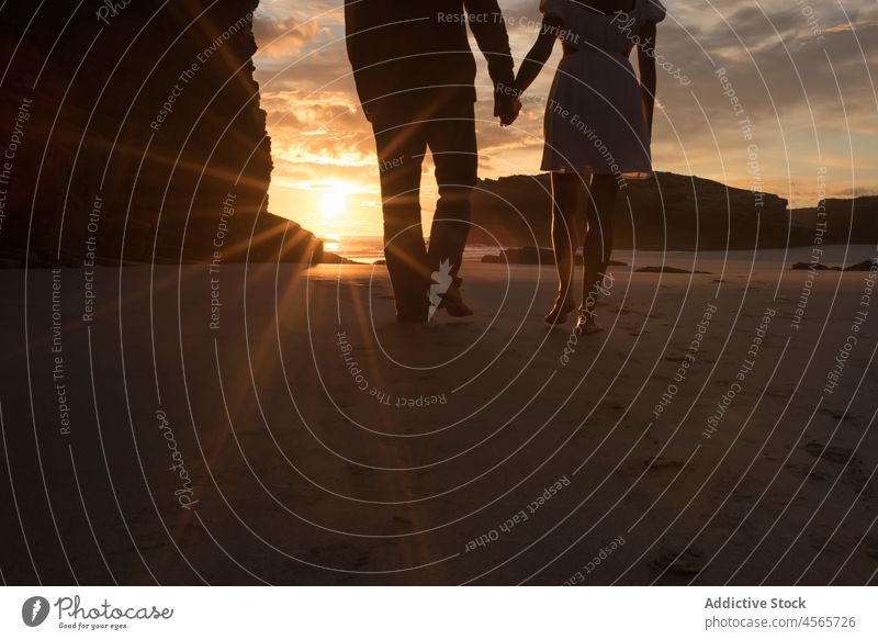 Anonymes Paar geht abends am Strand spazieren Silhouette Sonnenuntergang Zusammensein Dämmerung Ufer malerisch Spaziergang Abend Händchenhalten