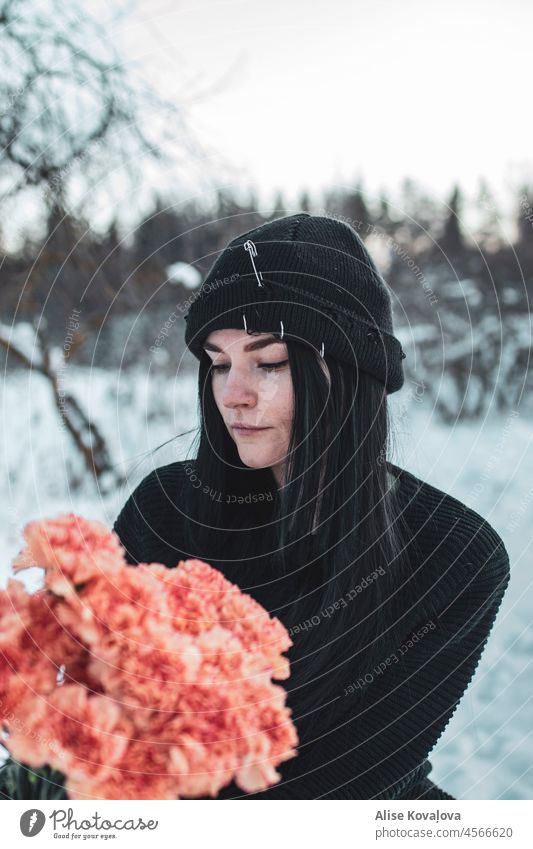 Geburtstag im Winter Blumen Mädchenporträt Schwarzes Haar schwarzer Hut Rosa Nelken Mädchen hält Blumen jung Frau Porträt kalt verschwommener Hintergrund