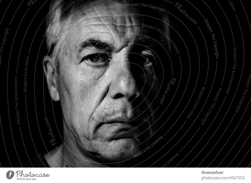 Porträt von Mann im Dunkel, ernst Mensch Schwarzweißfoto Gesicht Erwachsene Nahaufnahme Männergesicht Blick in die Kamera Kontrast Falten alter Mann streng