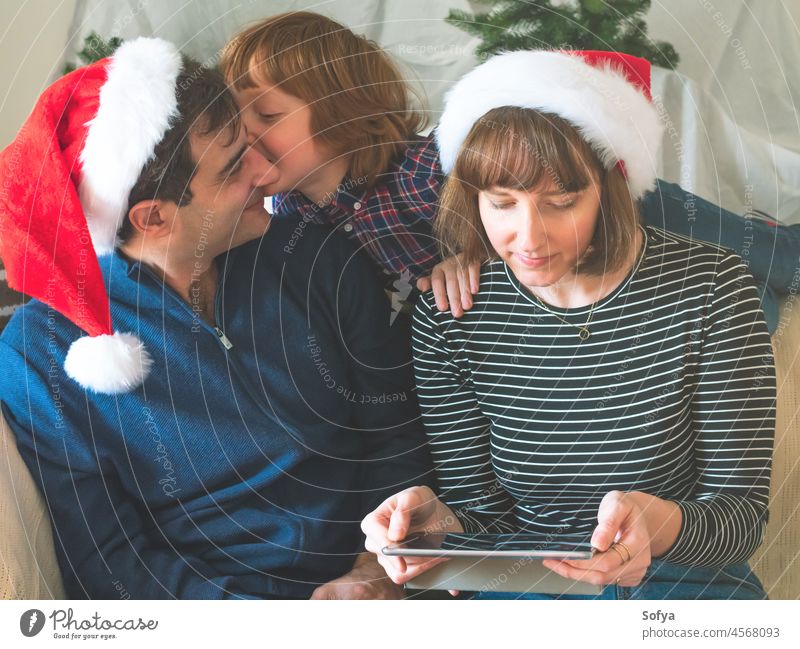 Mutter, Vater und Sohn in Weihnachtsmützen an den Weihnachtsfeiertagen Weihnachten Papa genießen Liebe Tablette Dezember Apparatur Lifestyle online Lächeln Kind