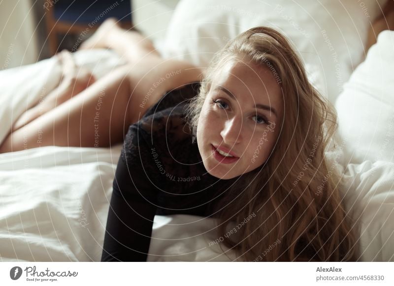 Portrait einer jungen, blonden, langhaarigen Frau, die im Bett liegend in die Kamera schaut Jugendlichkeit gesund Gesichtsausdruck Wärme drinnen Lifestyle Sinne