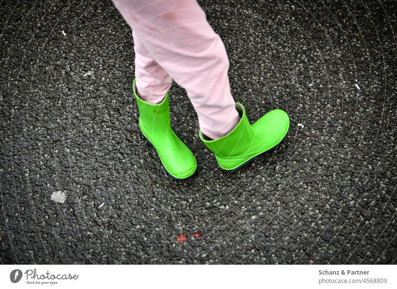 grüne Gummistiefel an verknoteten Beinen Kind spielen rosa Hose umkehren verdreht Füße Schuhe Stiefel nass