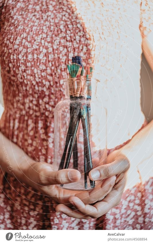 Junge Frau Künstler Hände greifen eine Flasche mit Farbe Stifte und Pinsel gefüllt, bereit für die Malerei Acryl. Künstlerische Konzepte, Künstler Konzept. Schönheit Kleid Konzept Jahrgang mit Sonne Bohne