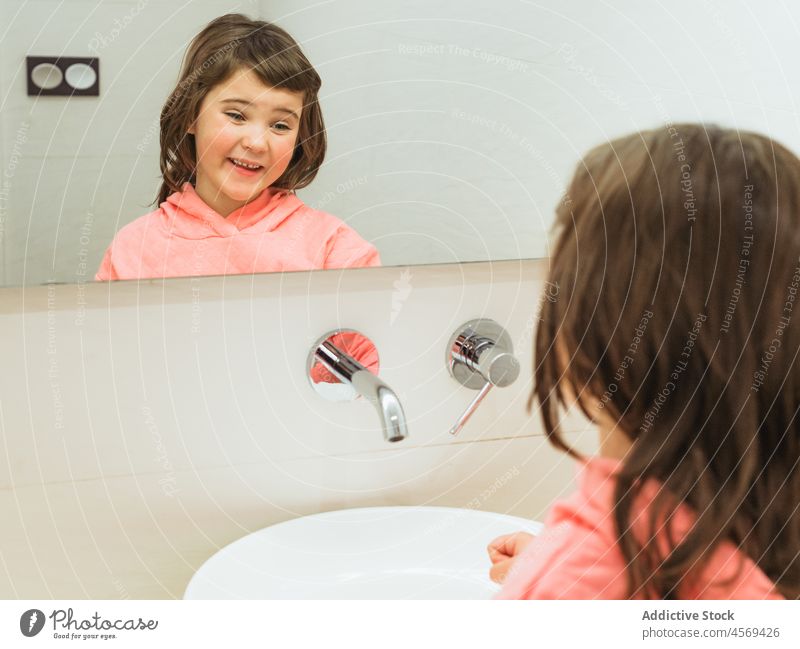 Fröhliches Mädchen betrachtet den Spiegel im Badezimmer Kind Hygiene täglich Routine heimisch Reflexion & Spiegelung reflektieren positiv Lächeln Optimist