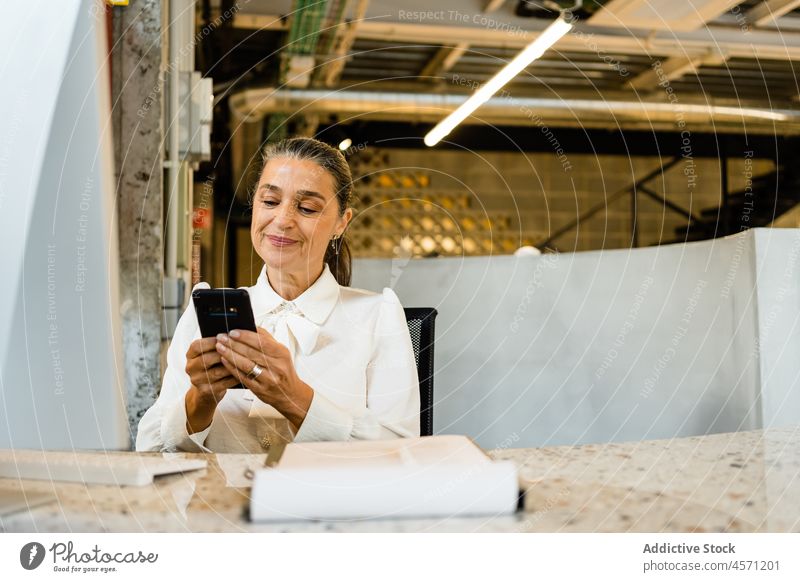 Glückliche Frau, die im Büro eine SMS auf ihrem Smartphone schreibt Browsen benutzend Kommunizieren Geschäftsfrau Telefon Arbeit Arbeiter Surfen Apparatur