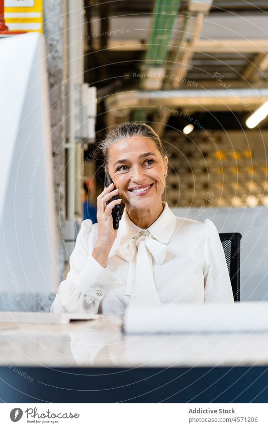 Fröhliche Frau, die im Büro mit ihrem Smartphone spricht Telefonanruf Gespräch diskutieren Kommunizieren Arbeit Arbeiter Arbeitsbereich Unternehmen Mitarbeiter