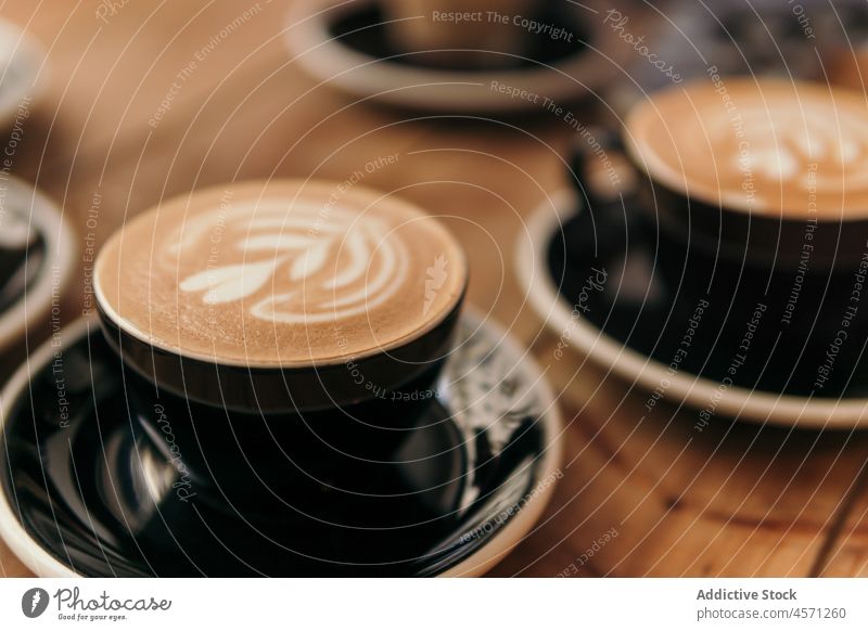 Tassen mit appetitlich schäumendem Cappuccino auf einem Holztisch serviert Latte Art dienen Kaffeehaus Café Getränk Koffein trinken aromatisch brauen