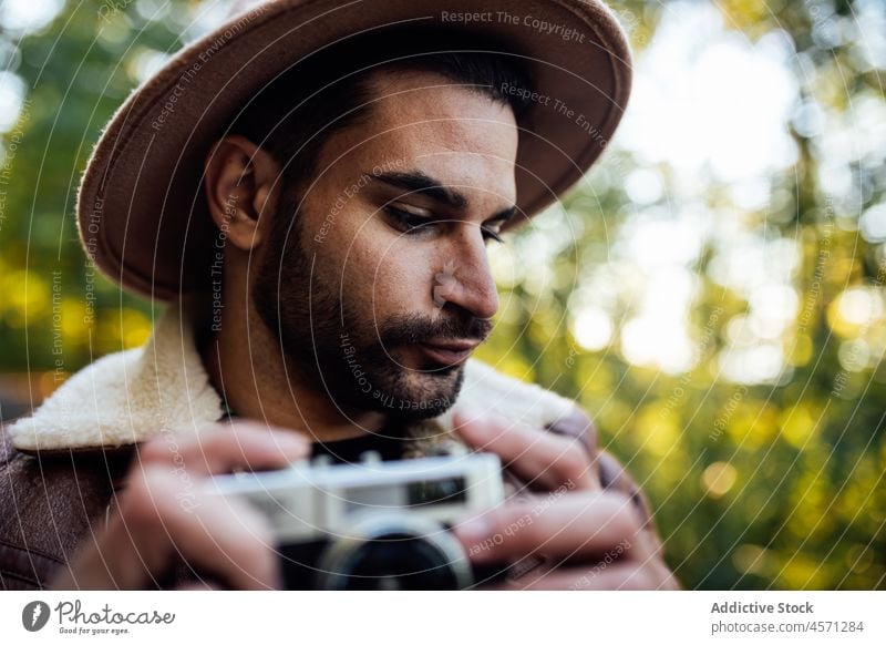 Mann stehend mit alter Fotokamera auf der Straße Baum Weg Fotoapparat fotografieren Fotograf Natur Hain Erholung Stil Porträt Abenteuer Ausflug Freizeit Outfit
