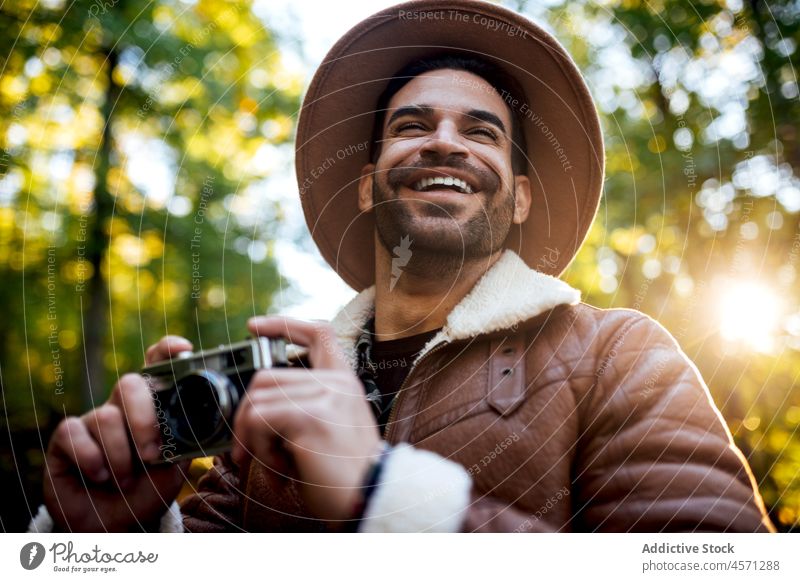 Mann stehend mit alter Fotokamera auf der Straße Baum Weg Fotoapparat fotografieren Fotograf Natur Hain Stil Porträt Abenteuer Ausflug Freizeit Outfit trendy