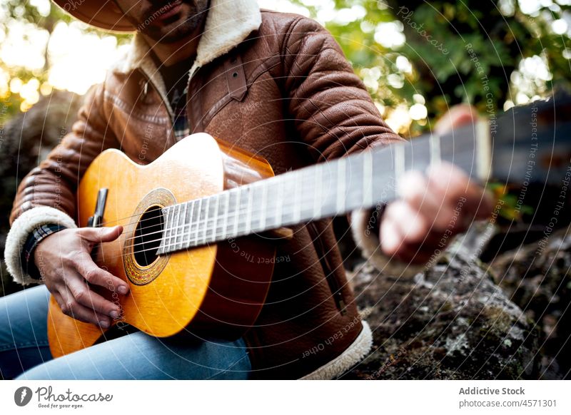 Hipster-Typ spielt Gitarre im grünen Wald in der Natur Mann Musik spielen Instrument Gesang Baum Hobby Gitarrenspieler Musiker männlich Wälder Melodie Hut