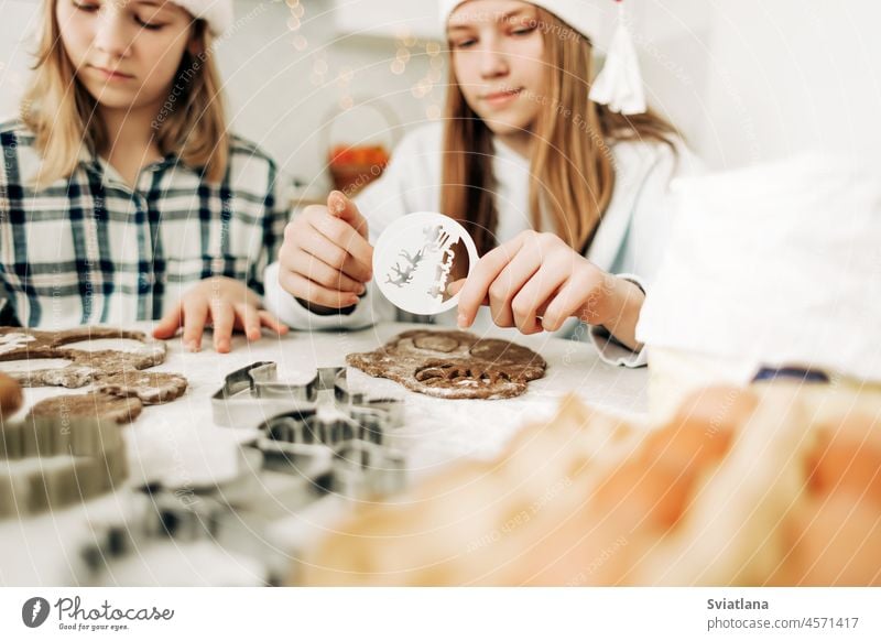 Nahaufnahme-Schablonen zum Zeichnen von Plätzchen oder Lebkuchen für Weihnachten oder Neujahr in den Händen von Mädchen Teigwaren Form Cookies Foto Kuchen Feier