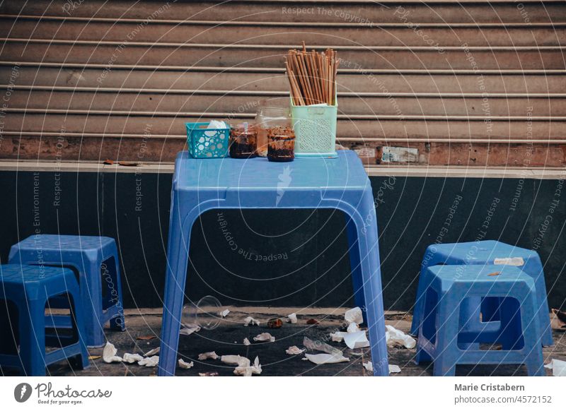 Blaue Plastikstühle und ein Tisch in einer Seitenstraße von Hanoi City, wo die traditionelle Pho Bo oder Rindfleischnudelsuppe serviert wird Textfreiraum