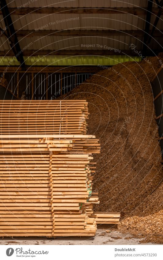 Gestapelte Holzlatten liegen vor einem riesigen Haufen an Holzspänen holzlatten Stapel stapeln Stapelung Sägespäne Ansammlung hölzern Abholzung Holzbretter