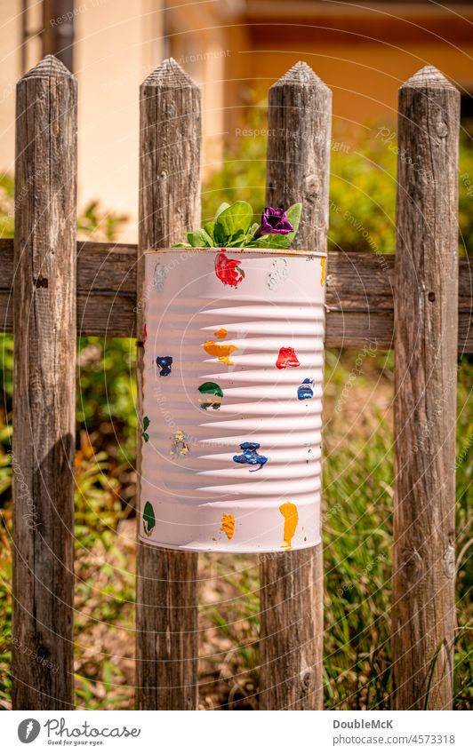 Angemalte, verzierte Blechdose als Blumentopf am Gartenzaun hängend Dose Holzzaun lattenzaun Zaun natürlich Außenaufnahme Farbfoto Menschenleer Tag schön