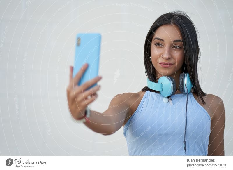 schöne Frau nimmt ein Selfie mit dem Smartphone mit den Kopfhörern auf ihrem Hals jung Handy Funktelefon Zelle Telefon Mobile Mobiltelefon Foto Fotografie Nizza